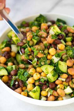 a white bowl filled with black eyed peas and cucumbers