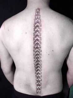 the back of a man with a tattoo on his upper and lower back, which has an intricate design