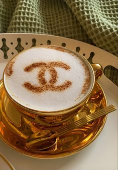 there is a gold plate with a cup and saucer that has a chanel logo on it