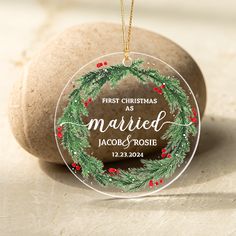 a personalized ornament hanging from a rock with a christmas wreath on it