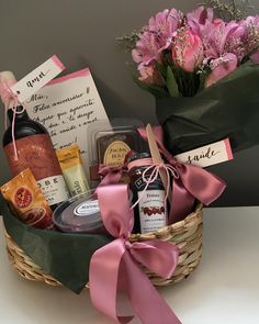 a basket filled with lots of different types of wine and liquors next to a bouquet of flowers