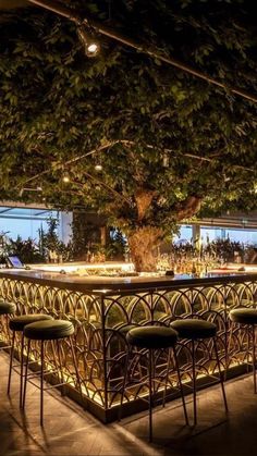 an outdoor bar is lit up at night with lights shining on the tables and stools