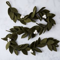 three green leaves and white flowers on a marble surface