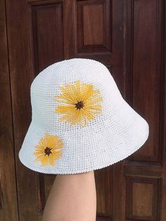 a person's foot wearing a white hat with yellow flowers on the brim