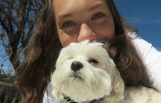 a woman holding a white dog in her arms