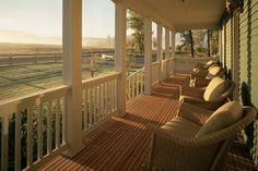 a porch with wicker furniture on it and a view of the countryside in the distance