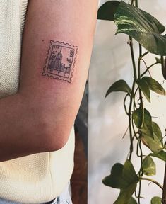 a woman's arm with a stamp on it and a plant in the background