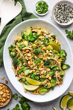 a white bowl filled with broccoli and nuts next to other ingredients on a table