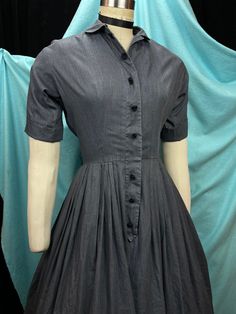 "1950s W:26 Vintage 50s Charcoal Grey Poly Cotton Shirtdress Button Up Short Sleeve Peter Pan Collar Flower Crochet Button Fit Flare skirt  Vintage 50s beautiful fit and flare classic pullover style shirt dress. Charcoal grey colored with chambray like texture on poly cotton fabric. Button up with placket and double buttons, functional and sewn on crochet black flowers. Little Peter Pan collar and short cuffed sleeve. Skirt pleated fit and flare. Photographed on fit form size 2, please check measurements, added red petticoat not included. MEASUREMENTS  Bust: 39\" Waist: 26\" Hips: free Bodice length: 16 1/2\" Skirt length: 25\"  Length: 42\" with 4\" hem available to let down Sleeve: 12\" (not cuffed) This is in good vintage condition, presents beautifully and is completely wearable as is! Classic A-line Vintage Dress With Buttons, Classic A-line Vintage Dress With Button Closure, 1950s Style Dresses With Buttons, Retro Vintage Dress With Button Closure, Fitted Retro Button-up Vintage Dress, Retro Fitted Button-up Vintage Dress, 1950s Style Knee-length Dress With Button Closure, 1950s Style A-line Vintage Dress With Buttons, Retro Semi-formal Dresses With Buttons