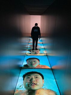 a man standing in the middle of a hallway with four images on it's floor