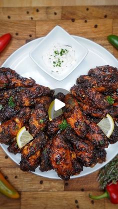 chicken wings on a plate with dipping sauce and vegetables around it, ready to be served