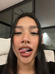 a woman with black hair and piercings on her nose is making a funny face