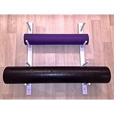 a black and purple yoga mat sitting on top of a wooden floor next to a metal bar