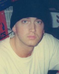 a man sitting at a table with a drink in his hand and wearing a beanie