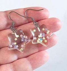 Resin clear star earrings, with glitter celestial stars inside. Star earrings, resin earrings. STAINLESS STEEL ear wires fish hooks. Boho hippy vibes, great for festivals & music concerts or parties *earring wires measure approx .6 of an inch, or just over half an inch *charm itself approx 3/4 of an inch long *STAINLESS STEEL earring wires fish hooks *charms are resin with glitter pastel rainbow confetti sparkles inside *comes in a gift box Star-shaped Resin Jewelry For Gifts, Star Shaped Resin Jewelry Gift, Trendy Star-embellished Jewelry Gift, Trendy Star Embellished Jewelry Gift, Trendy Star Embellished Jewelry For Gifts, Hippy Vibes, Sparkle Stars, Celestial Stars, Rainbow Confetti