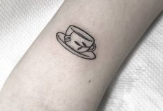 a small hat tattoo on the left inner forearm and wristband, which is drawn in black ink