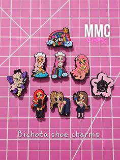 six different cartoon pins sitting on top of a pink surface