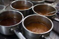 four pots filled with brown liquid sitting on top of a stove