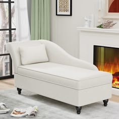 a white chaise lounge chair sitting in front of a fire place