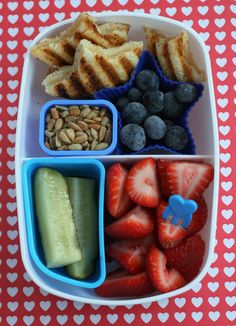 a bento box filled with fruits, vegetables and crackers on top of a table