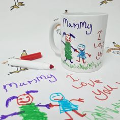 a coffee mug sitting on top of a table next to markers and crayons