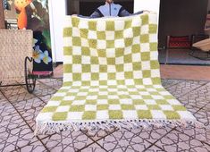 a man sitting in front of a green and white checkered blanket on top of a chair