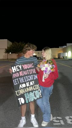 a man and woman holding a sign that says hey young and beautiful let the light in and be my cinnamon cider to hope