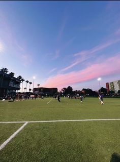 people are playing soccer on the field at sunset