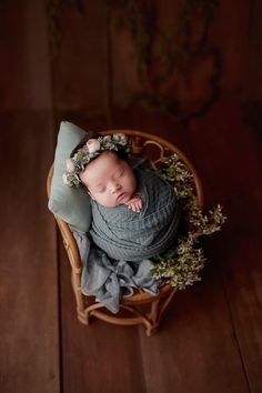 a newborn baby is wrapped in a blanket and laying on top of a wooden chair