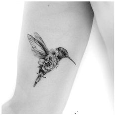 a small hummingbird with flowers on its back leg tattoo by the talented artist jane