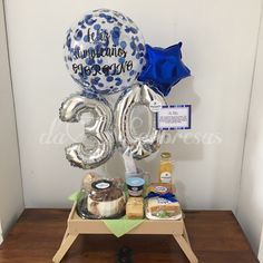 a table with balloons, cake and condiments on it in the shape of numbers