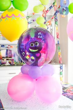 balloons and streamers hang from the ceiling above a table with an inflatable balloon