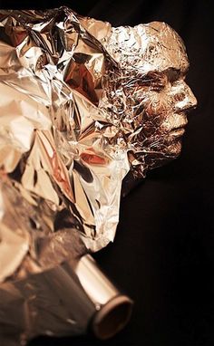 a sculpture made out of aluminum foil on a black background with the image of a man's head