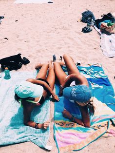 two women laying on towels at the beach