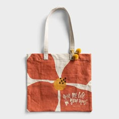 an orange and white tote bag with yellow pom poms