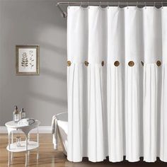 a white shower curtain with gold hardware on the top and bottom, in a bathroom