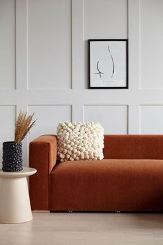 a living room with a couch, table and pictures on the wall above it that is decorated in white and orange