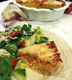 a white plate topped with lasagna next to a salad