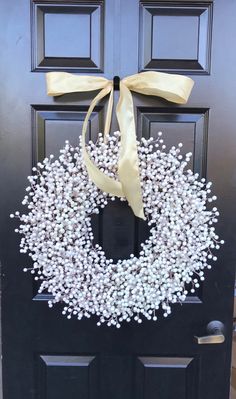 a black door with a white wreath and yellow ribbon hanging on it's side