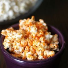 a purple bowl filled with popcorn on top of a table