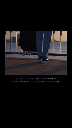 two people standing on top of a sidewalk next to the ocean with their feet in the air