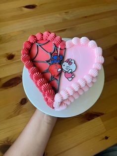 a heart shaped cake sitting on top of a white plate next to a person's hand