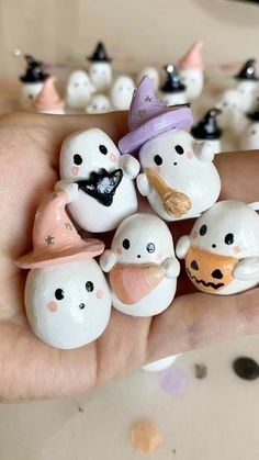 a hand holding a bunch of small white and black figurines with faces on them