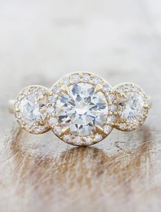 three stone engagement ring with diamond accents on the band and center surrounded by smaller round diamonds