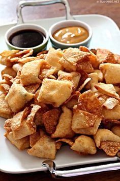 a white plate topped with fried food next to dipping sauces