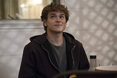 a young man sitting at a table in front of a mirror