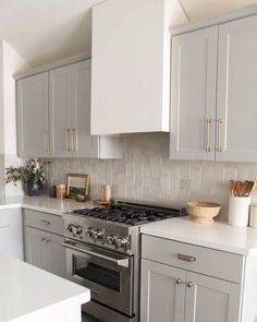 a kitchen with gray cabinets and white counter tops