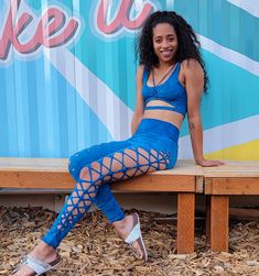 a woman sitting on a wooden bench in front of a pepsi sign wearing blue tights