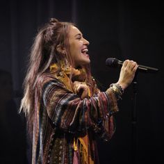 a woman with long hair singing into a microphone