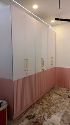 an empty room with pink and white lockers on the walls, and floor that has been stripped off